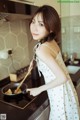 A woman in a white dress cooking food in a pan.