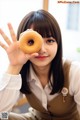 A woman holding a donut in front of her face.