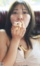 A woman sitting on a couch eating a piece of food.