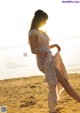 A woman standing on a beach next to the ocean.