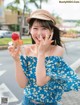 A woman in a blue top and hat holding an ice cream cone.