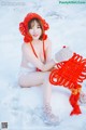 A woman sitting in the snow holding a red bag.