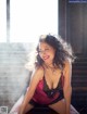 A woman in a pink and black lingerie sitting on a window sill.