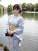 A woman in a blue kimono standing by a lake.