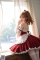 A woman in a red and white dress sitting on a window sill.