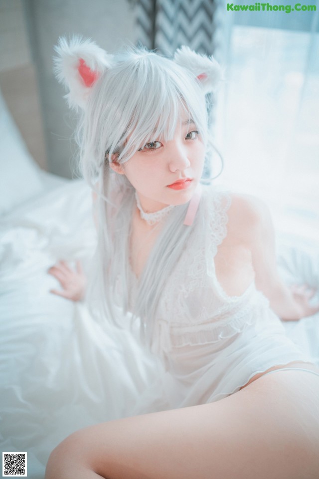 A woman in a white lingerie sitting on a bed.