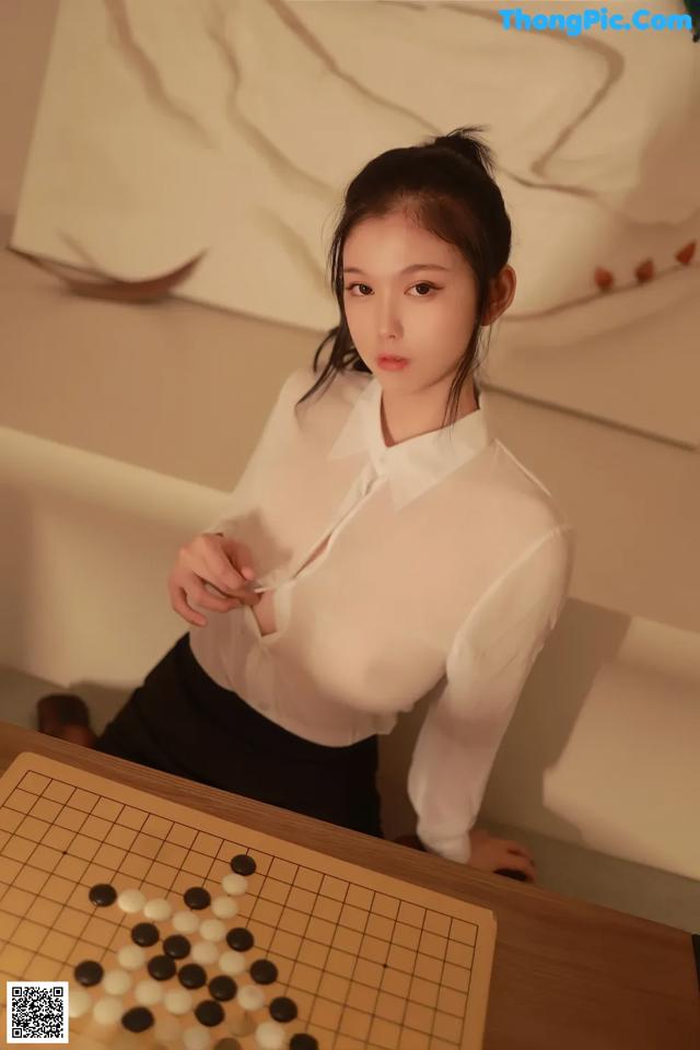 a woman in a white shirt and black skirt playing a game of checkers