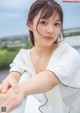 A woman in a white dress sitting on a bench.