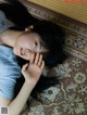 A young woman laying on a rug with her hand on her face.