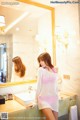 A woman standing in front of a mirror in a bathroom.