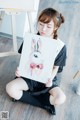 A woman sitting on the floor holding a painting of a rabbit.