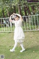 A young girl in a white dress standing in the grass.